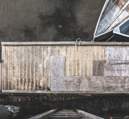 looking down on to  small boats tied to  a wooden bridge accessed by a ladder at the seaside 