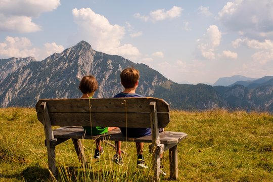 Boys, 8 and 10 years sitting on a bench, looking towards the Rinnkogel, Postalm, Salzkammergut, Salzburg, Austria, Europe