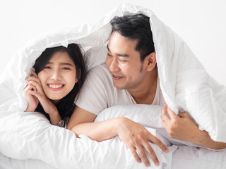 Happy Asian couple under white blanket together, lifestyle concept.