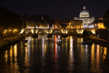 Fototapeta na wymiar A fabulous view of night Rome with a church, a bridge, a ship and the light of lanterns reflected in the Tiber River.