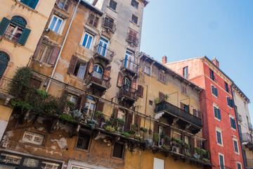 Fototapeta premium Beautiful traditional Italian building with flowers on balcony of medieval wall, Piazza delle Erbe, Verona, Italy