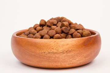 dry food in a wooden bowl on a white background