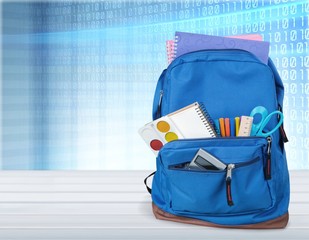 Colorful school supplies  in backpack on blackboard background