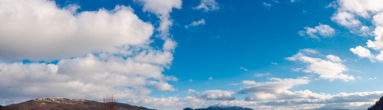 panorama of wonderful winter sky with fluffy clouds above the ridge. beautiful nature background, useful for compositing