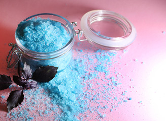 Sea salt of blue color in a glass jar on a pink background..