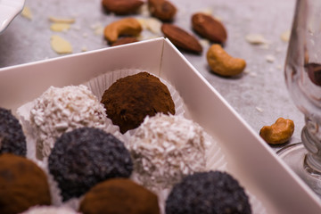 Candy in a white box close-up. Brown round candies, nuts, cinnamon