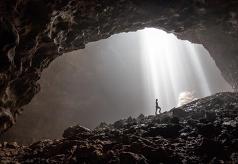 A silhouette inside the beautiful cave Goa Jomblang in East Java, Indonesia - obrazy, fototapety, plakaty