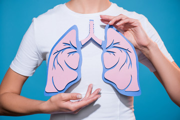 partial view of woman in white tshirt with paper crafted lungs on blue backdrop - obrazy, fototapety, plakaty