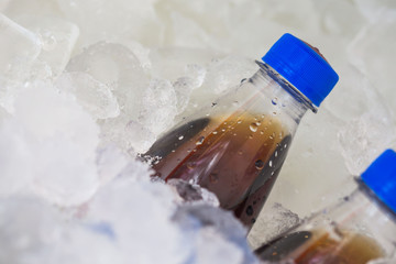  soda in cold of plastic bottle with blue Bottle Caps on ice
