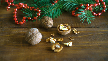 Obraz na płótnie Canvas Christmas background, walnuts, shell, fir tree branch and red bead balls Christmas decoration in shape of a heart on rustic wooden table. Empty space for text, New Year theme concept.