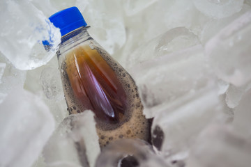  soda in cold of plastic bottle with blue Bottle Caps on ice