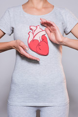 partial view of woman with paper crafted heart on tshirt on grey backgroun