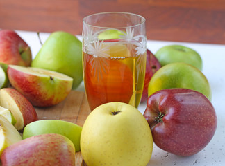  Apple juice in a glass and apples on the table.