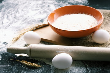 Dark Baking background with white eggs and flour.Dark blue background with a wooden spoon flour,eggs, flour and rolling pin. The process of baking, cooking.Top view, space for text.