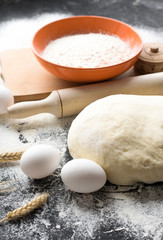 Dark Baking background with white eggs and flour.Dark blue background with a wooden spoon flour,eggs, flour and rolling pin. The process of baking, cooking.Top view, space for text.