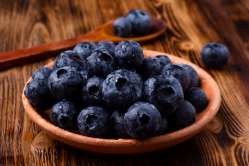 bog whortleberry in a clay cup with a wooden spoon on a wooden table