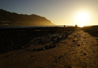 Silhouette of two men at sunset on the beach at Gordons Bay South Africa
