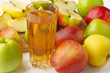  Apple juice in a glass and apples on the table.