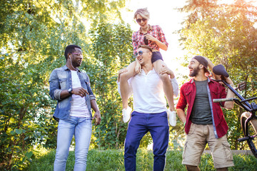 Fototapeta premium Happy adult guys and girls in casual wear enjoying a long walk excursion at the Botanical Garden.