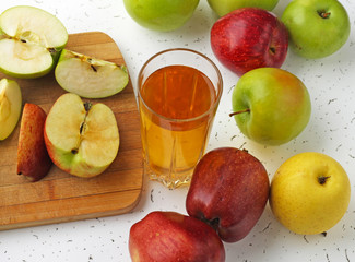  Apple juice in a glass and apples on the table.