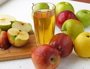  Apple juice in a glass and apples on the table.