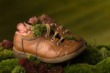 Newborn baby sleeping in old brown shoes