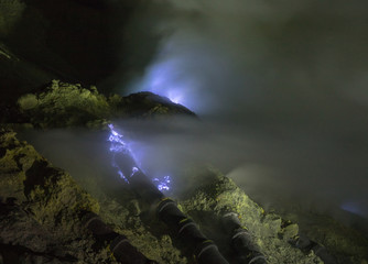 Blue Flame from the Mount Ijen sulfur mines inside the crater next to the emerald lake in East Java, Indonesia
