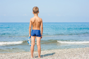 Little boy  holding mask and snorkel on the beach. Empty space for text © Ermolaev Alexandr