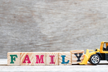 Fototapeta premium Toy bulldozer hold letter block y to complete word family on wood background
