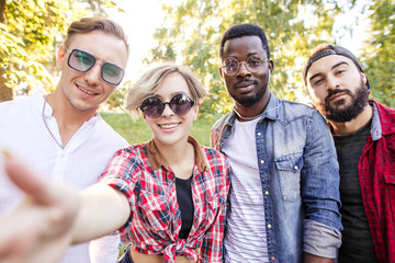 Group of multiracial friends dressed in casual summer clothing with smartphone having fun together...