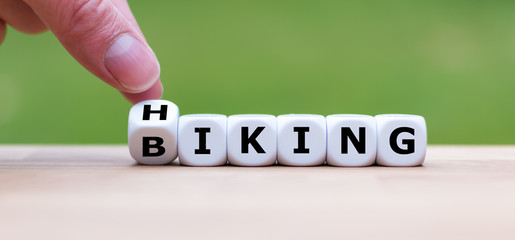 Hand is turning a dice and changes the word "hiking"to "biking"