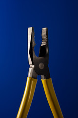 pliers with yellow handles on a blue background
