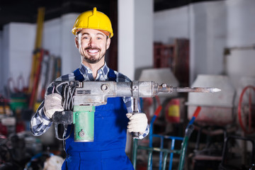 working man practicing his skills with pneumatic drill at workshop