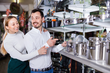 Young couple choosing new saucepan in dinnerware store