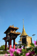 Fototapeta premium Architectural detail of Buddhist temple, Wat Traimit and Chinatown Gate over blue sky in Bangkok, Thailand