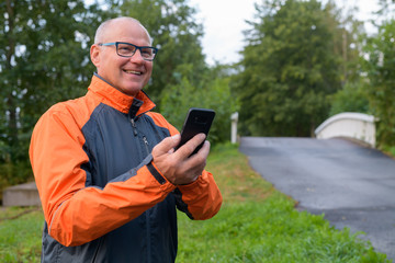 Obraz premium Happy Senior Man Thinking While Using Phone On The Side Of The Road