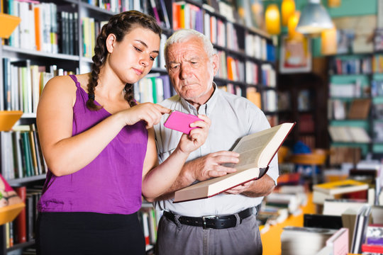 Mature person is choosing book while young teenage girl chatting