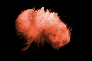 Red powder explosion on black background. Freeze motion of red dust particles splash on dark...