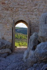 Blick durch altes Burgtor auf Olivenbäume und Weinreben