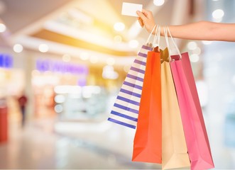 Woman with shopping bags and card on mall background