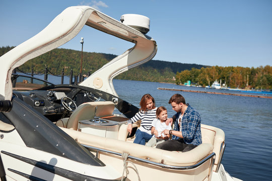 Family With Daughter Vacation Together On Sailboat In Autumn Lake