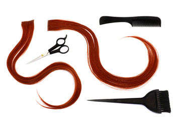 a strand of red hair, brushes, scissors, comb, hairdressing tools on a white background, isolated