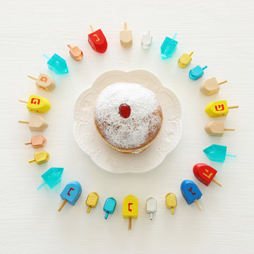Image of jewish holiday Hanukkah with wooden dreidels colection (spinning top) and doughnut over white background.