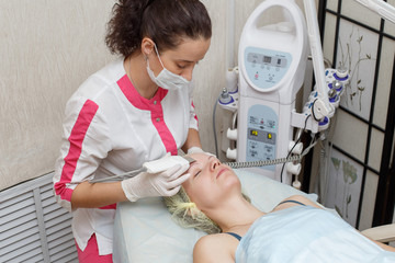 Cosmetologist doing procedure cleaning of face with ultrasonic scrubber