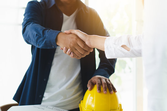 Successful deal, male architect shaking hands with client in construction site after confirm blueprint for renovate building.