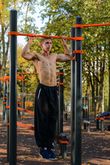 Fitness man doing stomach workouts on horizontal bar