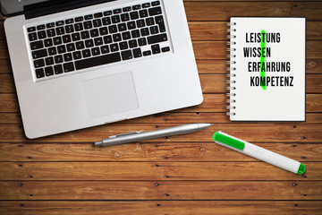 Kreuzwort TEAM aus motivierenden Begriffen auf einem Notizbuch am Arbeitsplatz