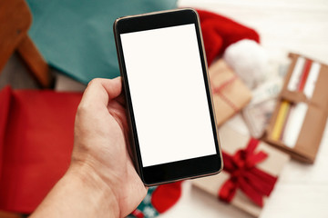 Hand holding phone with empty screen on background of credit cards and money in wallet, bags, clothes, gifts. Space for text. Advertising app. Christmas shopping and sale. Special offer