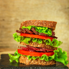 Sandwiches - bread, meat, basil, fresh leaves of lettuce on a wooden background. top view. copy...