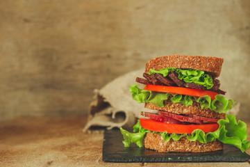 Sandwiches - bread, meat, basil, fresh leaves of lettuce on a wooden background. top view. copy space